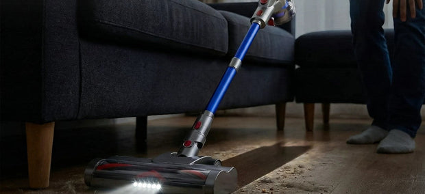 Moosoo AC1 Akku-Staubsauger saugt Tierhaare und Schmutz vom Holzboden neben dem Sofa