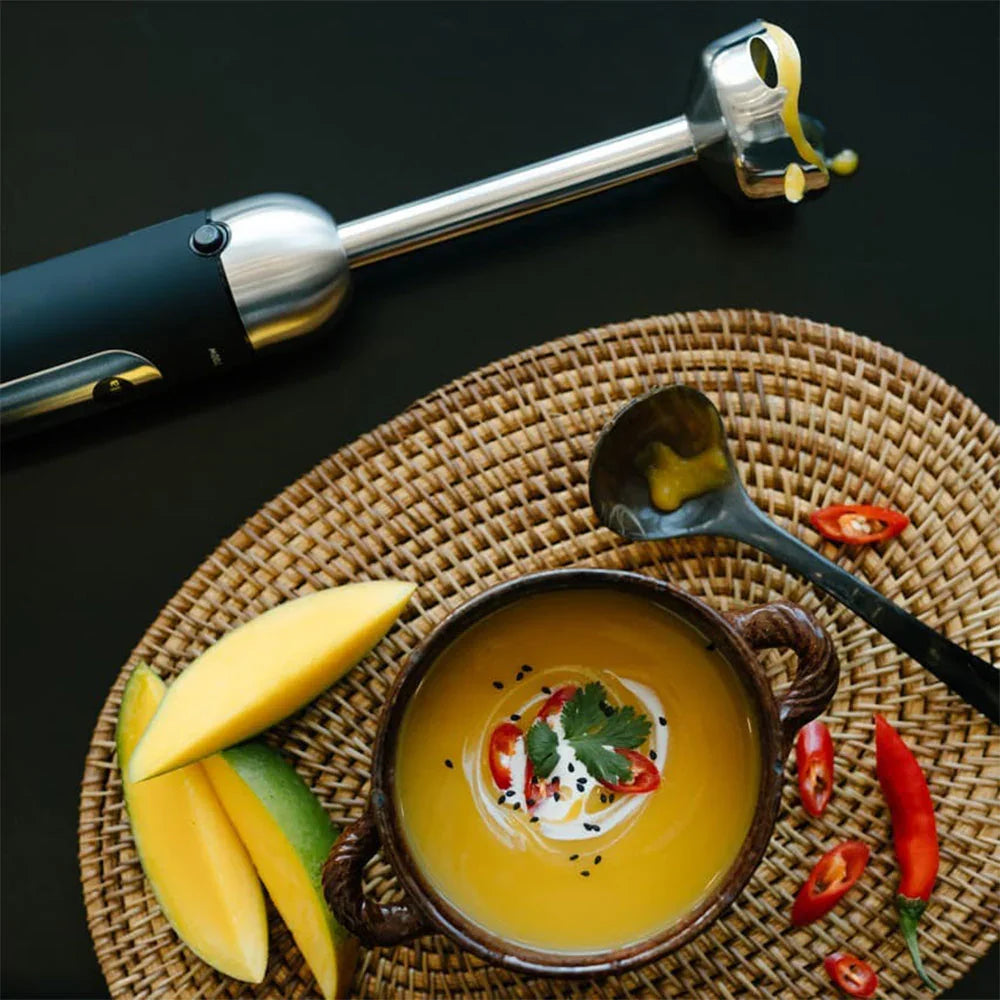 Immersion blender and bowl with thick yellow mixture, showing blending attachment