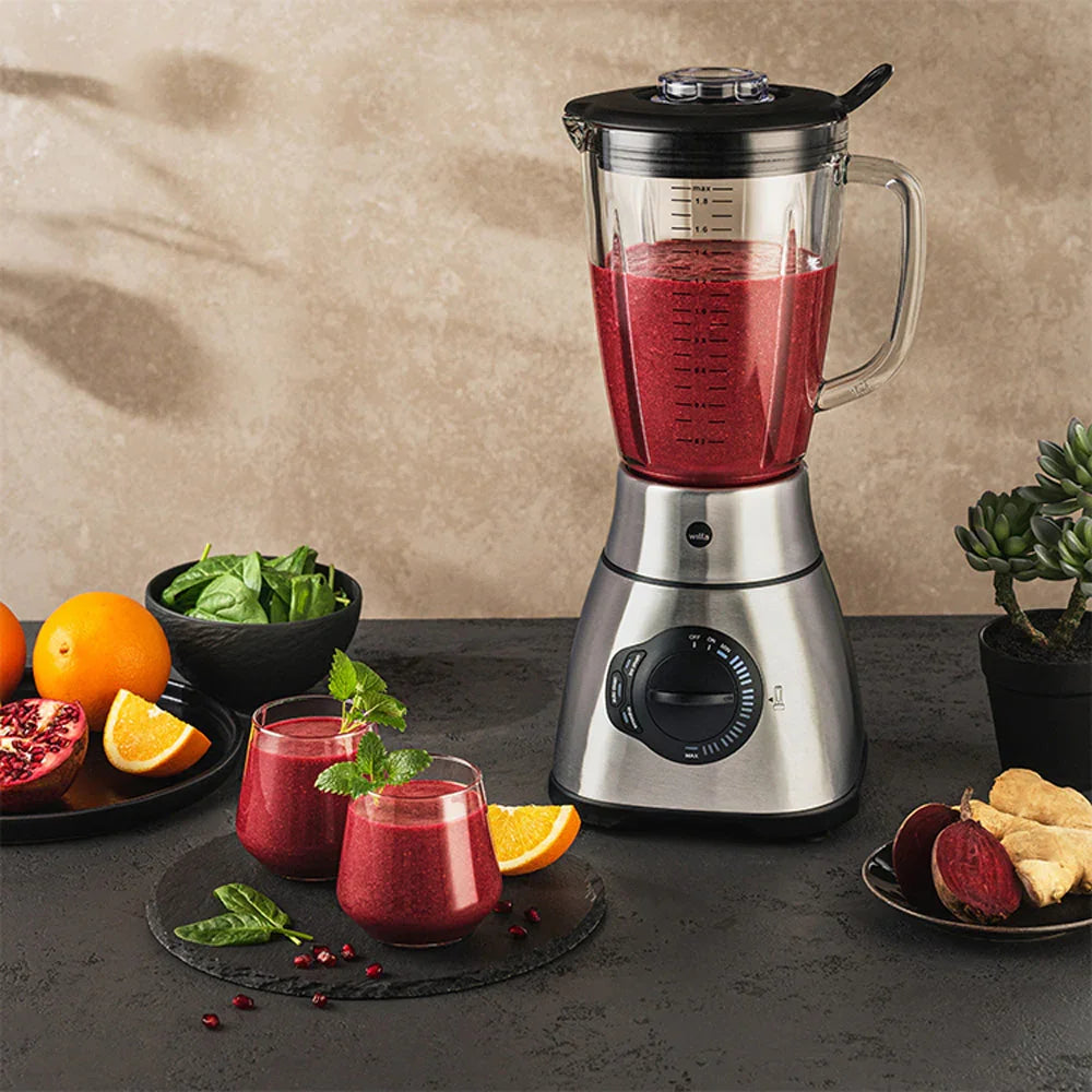 Stand mixer with glass jug filled with red smoothie and speed control dial