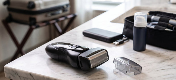 Moosoo RS726 Elektrorasierer mit Schutzkappe auf dem Hotel-Waschtisch, daneben Powerbank und Kulturtasche