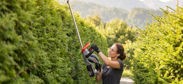 Akku-Heckenschere für hohe Hecken im Einsatz an einer hohen Gartenhecke – NIVAROQ