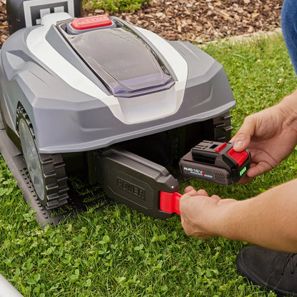 Mähroboter Robolinho Vision mit eingesetztem Akku, Hand am roten Schalter