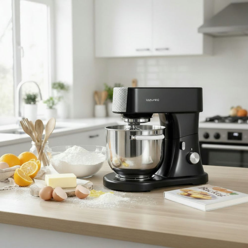 Küchenmaschine mit Edelstahlschüssel auf Arbeitsplatte, umgeben von Backzutaten wie Mehl, Eiern und Zitrusfrüchten.