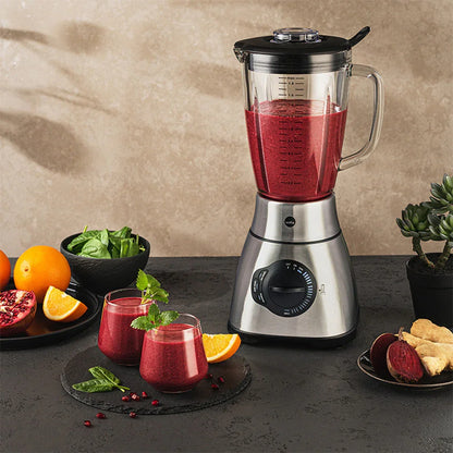 Stand mixer with glass jug filled with red smoothie and speed control dial